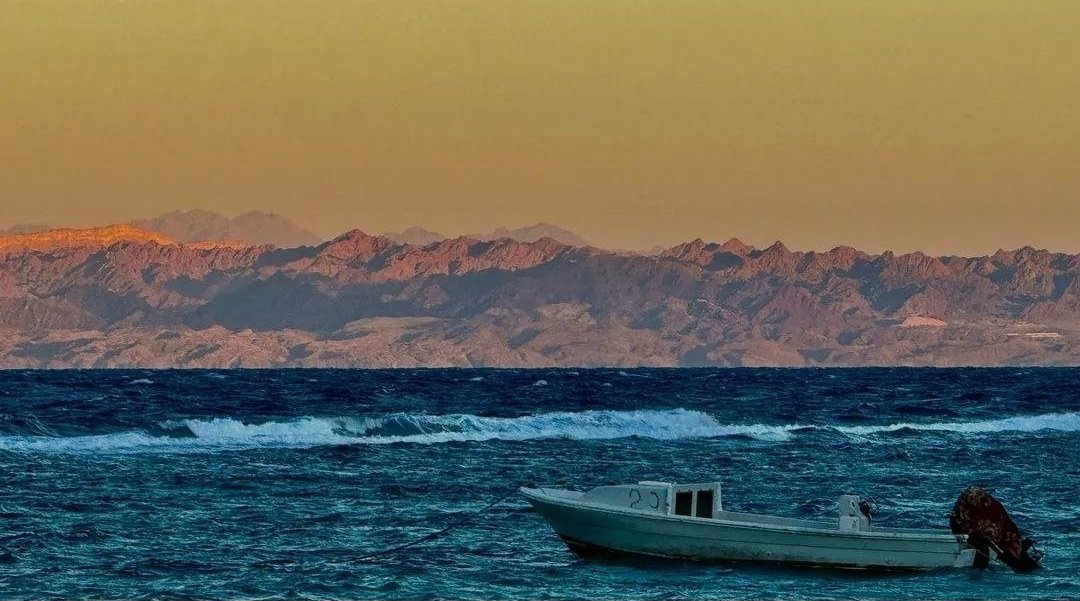 Fishing boat at sunset with mountains across the water
